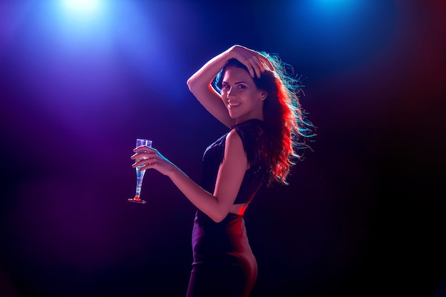 The beautiful girl dancing at the party and drinking champagne