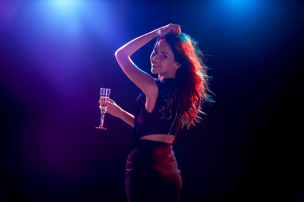 The beautiful girl dancing at the party drinking champagne