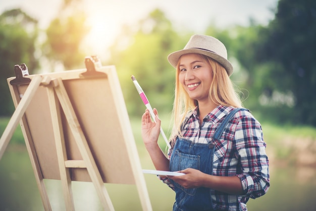 美しい女の子が公園で絵を描く