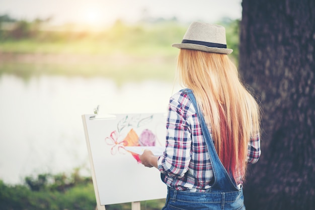 Beautiful girl draws a picture in the park