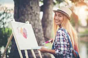 Free photo beautiful girl draws a picture in the park