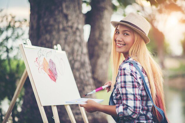 Красивая девушка рисует картину в парке