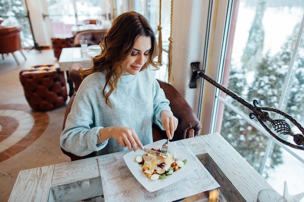 Beautiful girl eating Caesar salad in restaurant