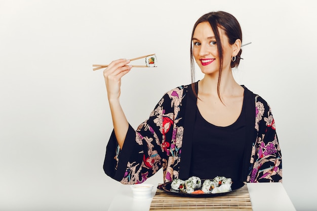 Foto gratuita bella ragazza che mangia un sushi in uno studio