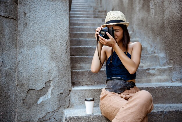 Beautiful girl in hat smiling, taking pictures, sitting at stairs.