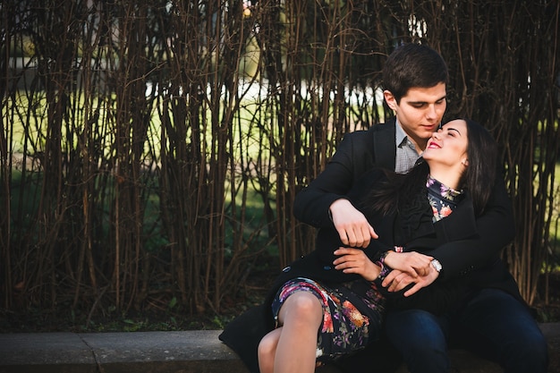 Beautiful girl and her boyfriend resting together on a bench in the park