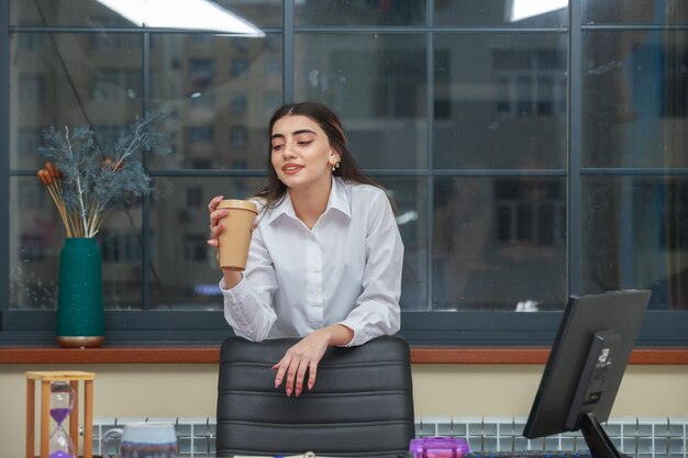 커피 컵을 들고 사무실에서 휴식을 취하는 아름다운 소녀 고품질 사진