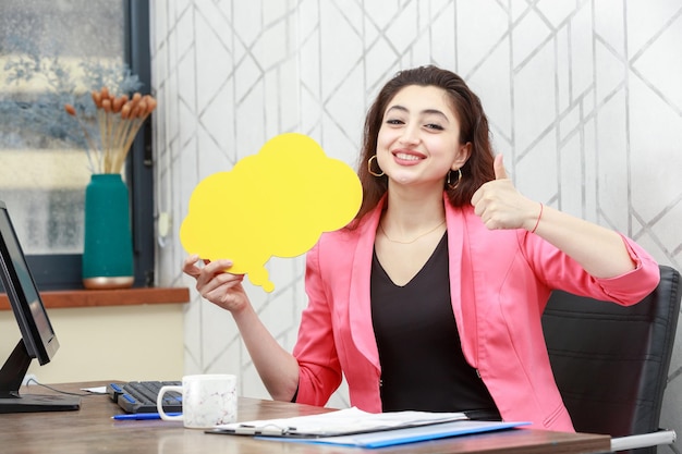 Beautiful girl holding yellow idea bubble in a cloud shape and gestures thumb up High quality photo