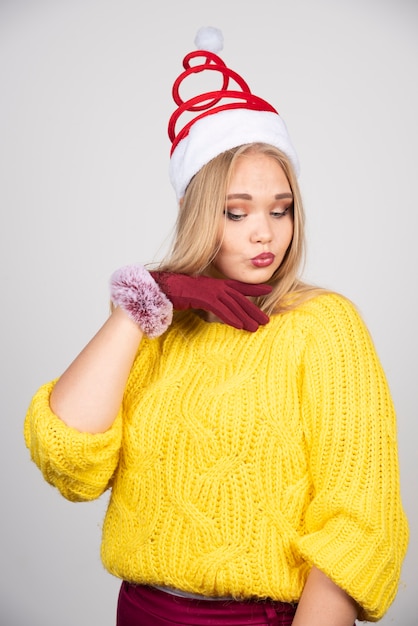 Бесплатное фото Красивая девушка в желтом свитере и представлять шляпу санты.
