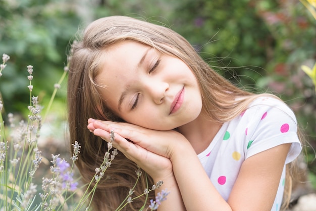 屋外で眠っている彼女の手に傾いている美しい少女