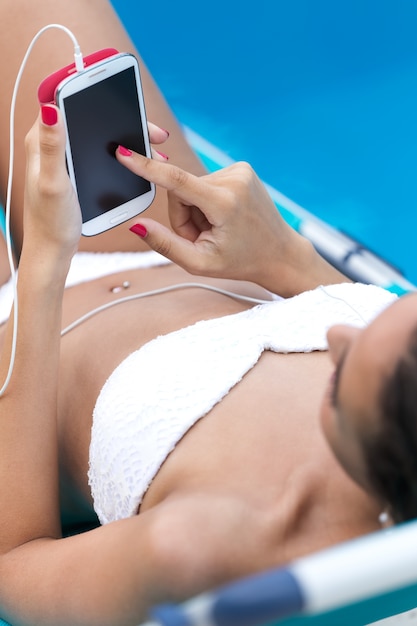 Beautiful girl listening to music in the swimming pool.