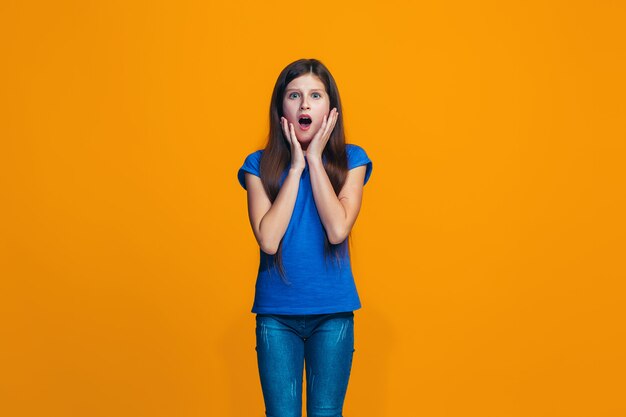 Beautiful girl looking suprised isolated on orange