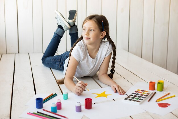 絵筆で床の絵星の上に横たわる美しい少女