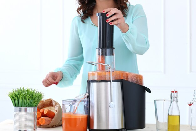 Beautiful girl making carrot juice