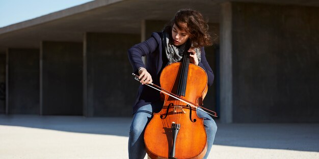 beautiful girl plays the cello with passion in a concrete environment