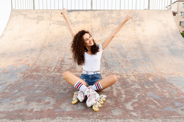 Bella ragazza in posa in rollerblades mentre era seduto