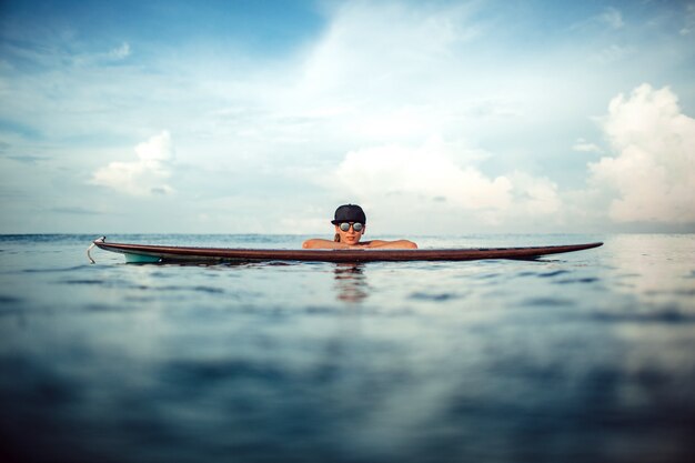 Красивая девушка позирует сидеть на доске для серфинга в океане