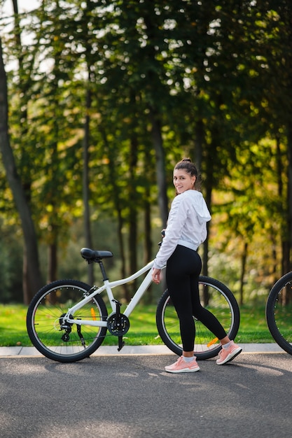 Beautiful girl posing at white bicycle. Walk in nature. Healthy lifestyle.