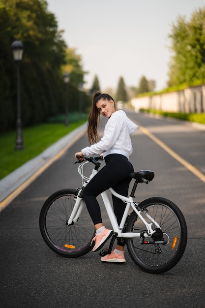 Beautiful girl posing at white bicycle. Walk in nature. Healthy lifestyle.