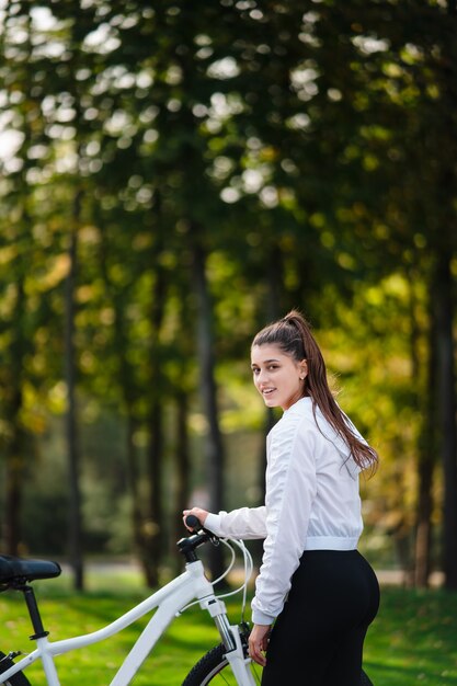 Beautiful girl posing at white bicycle. Walk in nature.