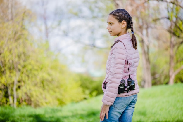 Foto gratuita bella ragazza in posa con il suo binocolo nel parco