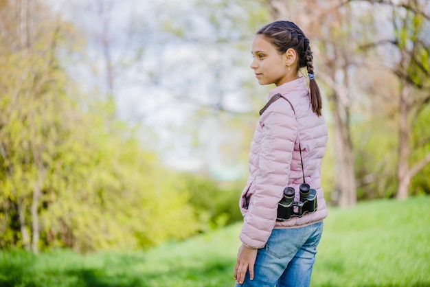 Beautiful girl posing with her binoculars in the park