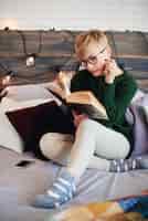 Бесплатное фото Красивая девушка, читающая книгу в постели