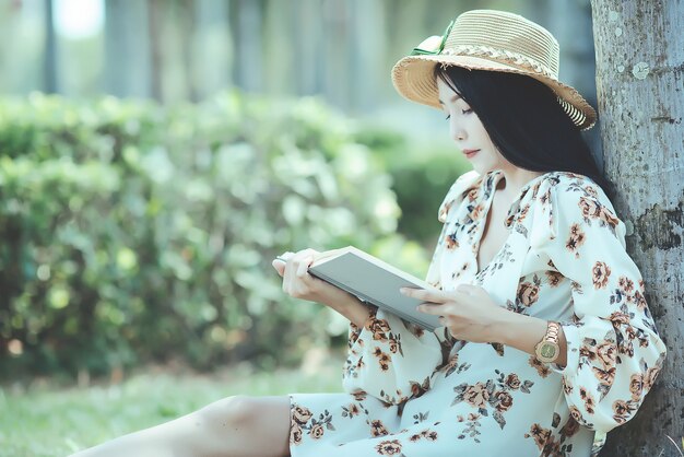 beautiful girl reading book at park in summer sun light