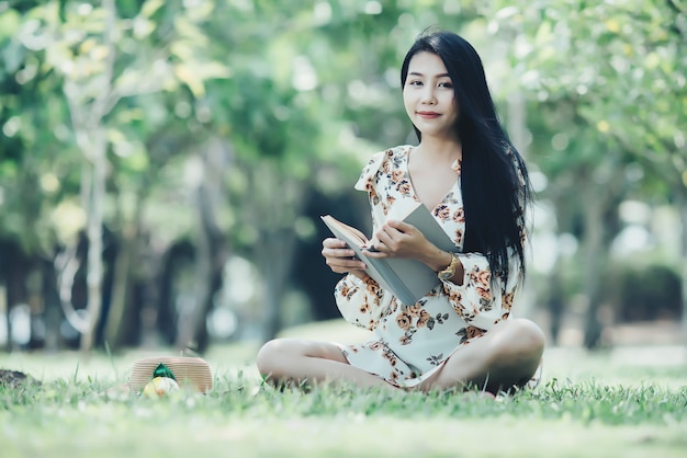 beautiful girl reading book at park in summer sun light