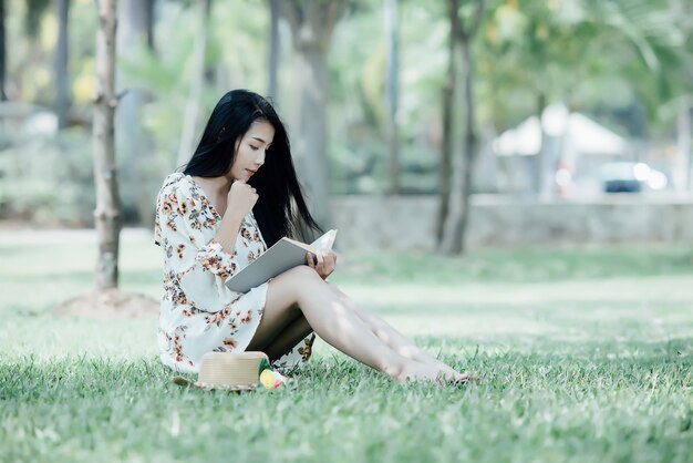 beautiful girl reading book at park in summer sun light