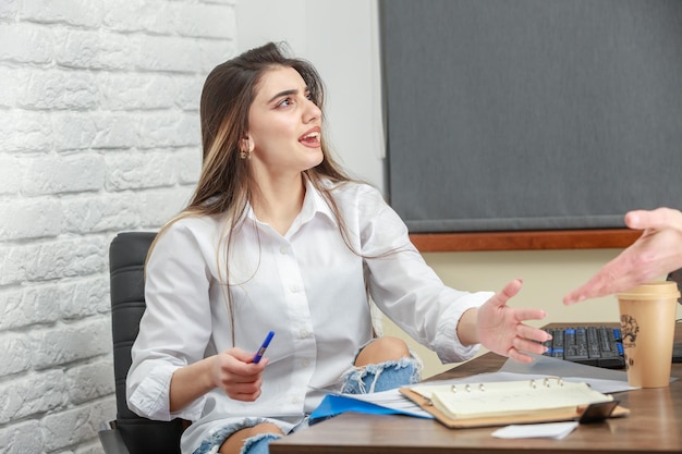 A beautiful girl sitting behind the desk and talking to someone