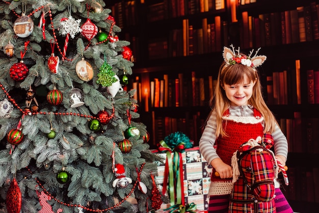 クリスマスツリーの近くの趣味の良い服を着た美しい少女