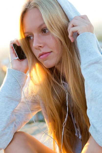 Beautiful girl sitting on the roof and listening to music.