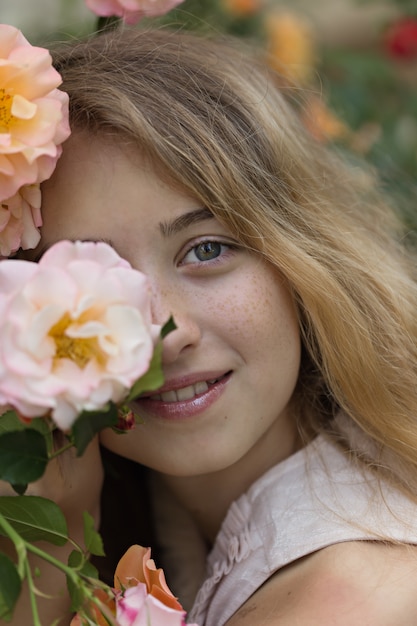 Beautiful girl sitting and smiling near the flowers, outside during daytime.