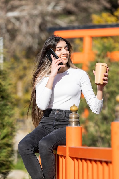 A beautiful girl sitting on the street and talking on the phone High quality photo