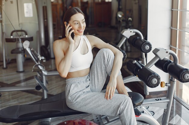 A beautiful girl sitting with phone in a gym