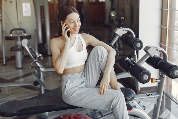 A beautiful girl sitting with phone in a gym