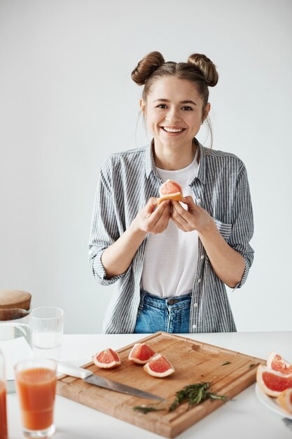 Beautiful girl smiling holding grapefruit piece over white wall. Healthy fitness nutrition.