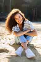 Free photo beautiful girl smiling while sitting on the sand