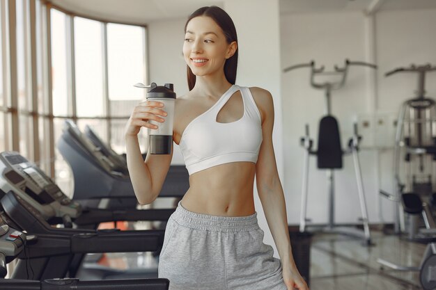 A beautiful girl standing in a gym with bottle of water