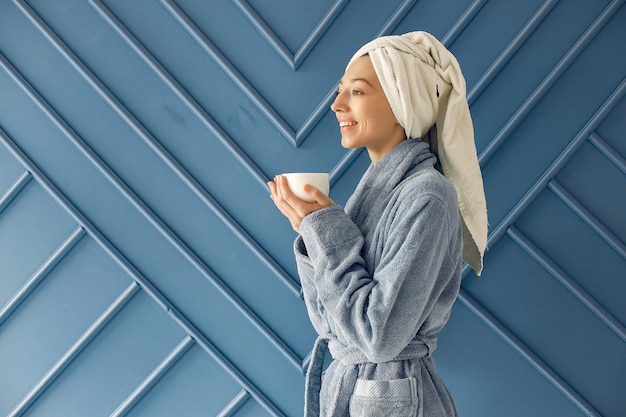 Free photo beautiful girl standing in a studio in a blue bathrobe