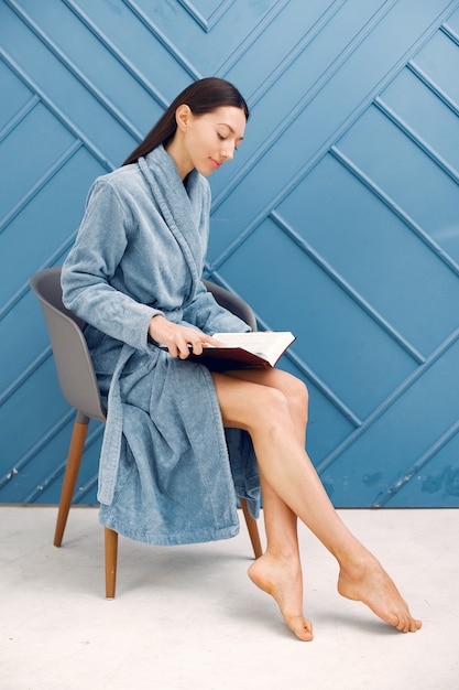 Beautiful girl standing in a studio in a blue bathrobe