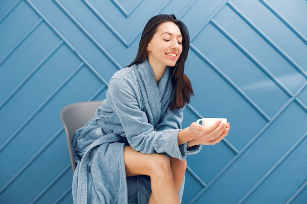 Bella ragazza in piedi in uno studio in un accappatoio blu