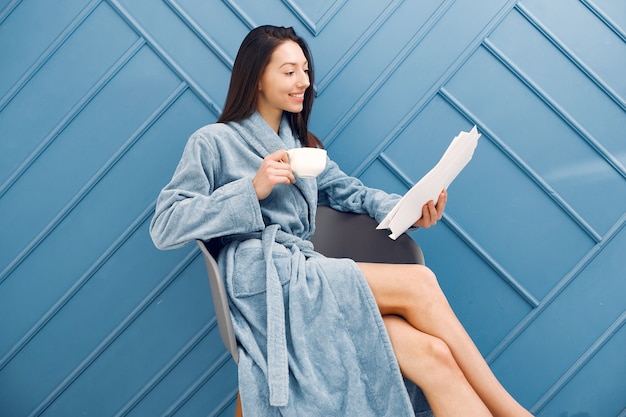 Beautiful girl standing in a studio in a blue bathrobe