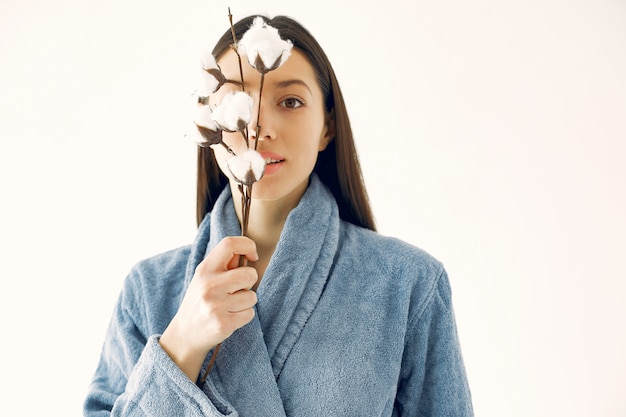 Bella ragazza in piedi in uno studio con fiori di cotone