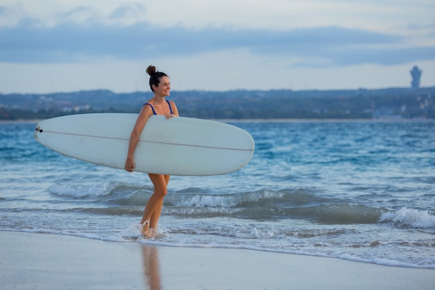 Free photo beautiful girl stands on the beach with a surfboard.