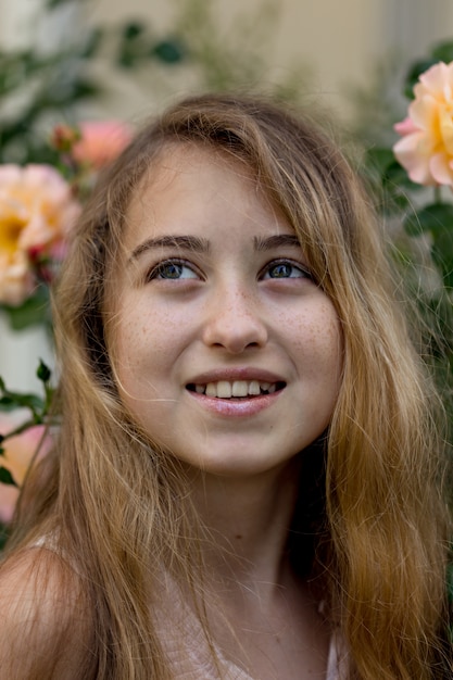 Free photo beautiful girl staring and smiling near flowers outside during daytime .