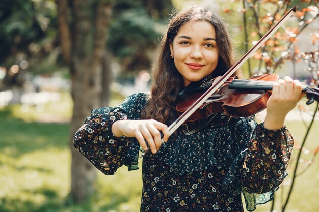 Beautiful girl in a summer park with a violin