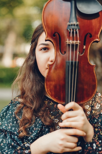 Beautiful girl in a summer park with a violin