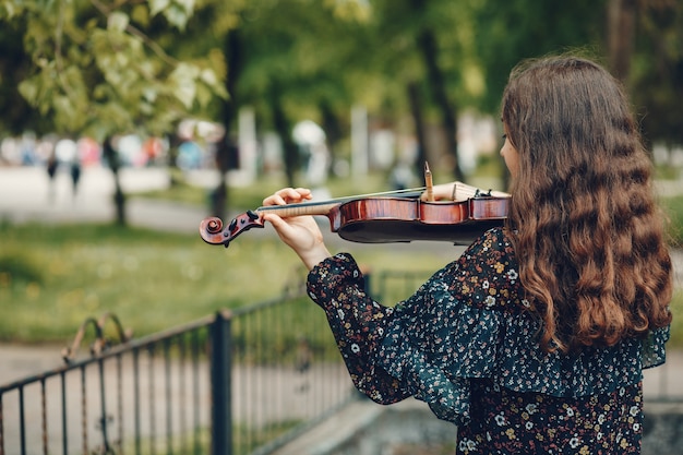 Bella ragazza in un parco estivo con un violino